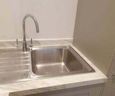 Professional mastic man applying silicone sealant in a UK kitchen.